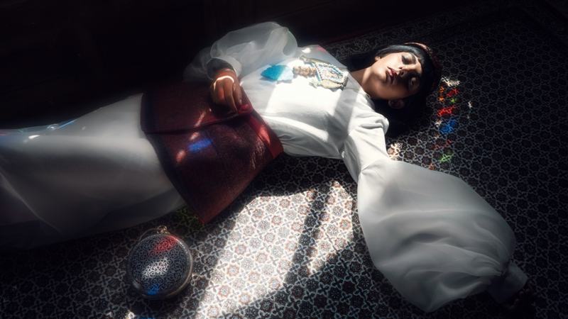 Person lying on a patterned rug with a large metallic object nearby

